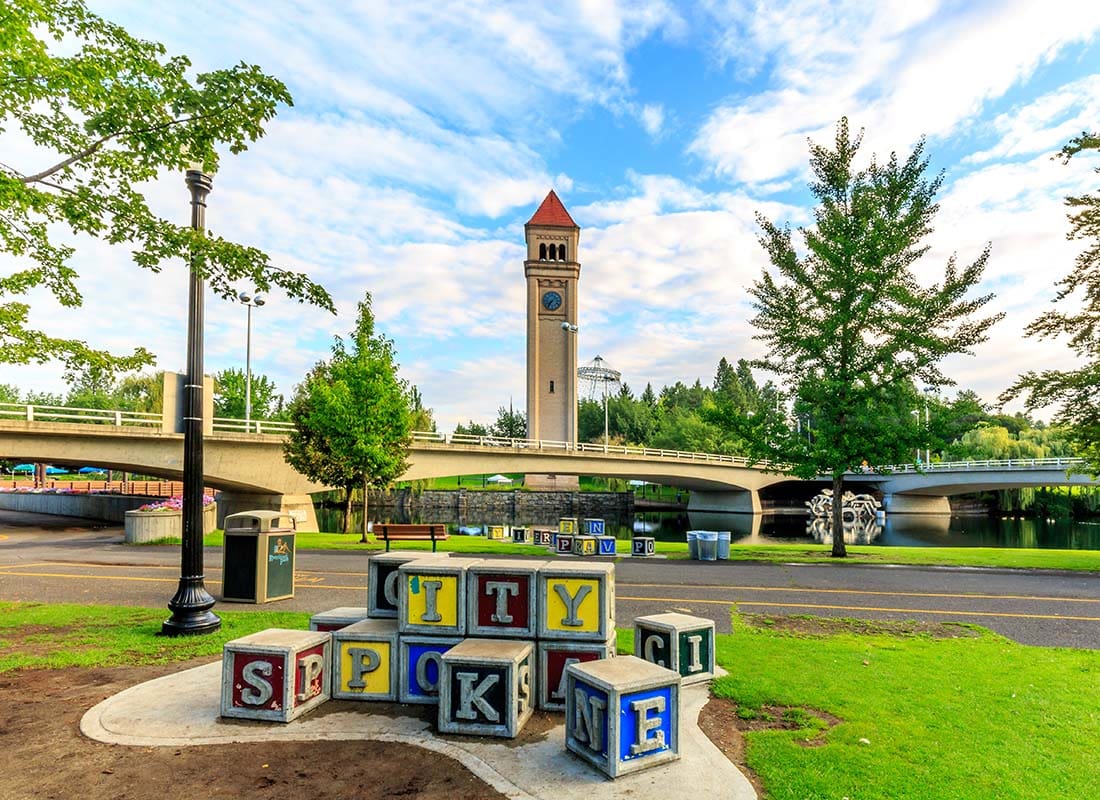 Local Resources - Colorful City of Spokane Blocks in a Park with Green Foliage with the Spokane Clock Tower in the Background on a Sunny Day