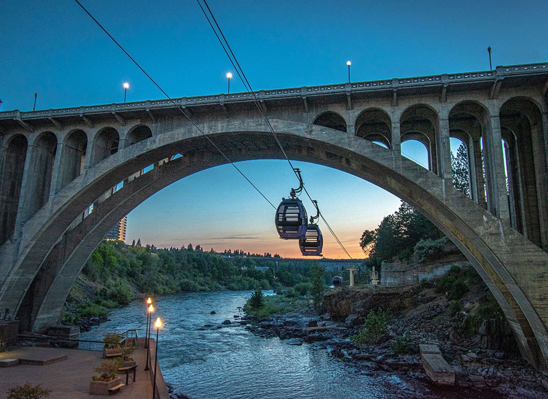 Service Center - View of Tram Cars Going Under an Archway in a Bridge Over the River in the Evening in Spokane Washington