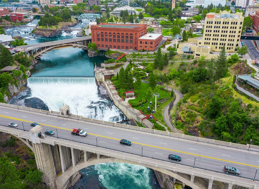 We Are Independent - Aerial View of Cars Driving on a Bridge Across the River with Views of Commercial Buildings in Downtown Spokane Washington